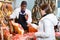 Seller in butcher shop, cutting jamon for female customer