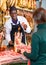 Seller in butcher shop, cutting jamon for female customer