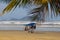 A seller of clothes, balls, swimwear and umbrellas walks on yarn of the Atlantic Ocean in Brazil. Paradise beach with palm trees