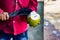 seller cutting a raw coconut shell with sickle to take out coconut water.