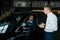 The seller demonstrates the interior of the car to buyers. Caucasian couple chooses a car.