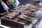 Seller grilling tasty bbq meat with wooden skewers on fire