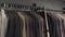 The seller removes the handmade jacket from the hanger. Row of men`s suit jackets hanging in closet