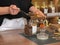 The seller of the store girl pours fragrant tea from different herbs with a spoon from a glass jar with a paper bag. Business