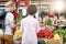 Seller woman offers fresh and organic vegetables at the green market or farmers market stall.  Young buyers choose and buy