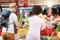 Seller woman offers fresh and organic vegetables at the green market or farmers market stall.  Young buyers choose and buy