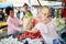 Seller woman selling fresh and organic vegetables at the green market or farmers market stall.  Young buyers choose and buy