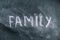 The semi-erased word FAMILY on the black chalkboard. Handwritten word. Fuzzy letters on black surface