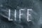 The semi-erased word LIFE on the black chalkboard. Handwritten word. Fuzzy letters on black surface