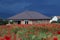 Semi-finished, half-finished house with red poppy field