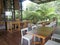 Semi interior of restaurant, wooden furniture, wooden ground, glass building, greenery view,