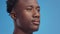 Semi profile portrait of young confident serious african american man looking aside, blue studio background, free space