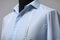 Semi-ready shirt with tailor`s measuring tape on mannequin against grey background, closeup