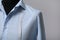 Semi-ready shirt with tailor`s measuring tape on mannequin against grey background, closeup