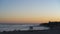 Semi silhouetted figures linger on beach during sunset, Natural Bridges Park