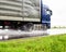 Semi-trailer semitrailer transports cargo on a wet road from rain in summer, close-up. Slippery road, trucking industry