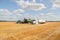 Semi truck and farm machinery parked in a field at harvest