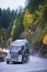 Semi truck trailer with cargo on winding autumn reoad in rain