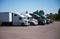 Semi-trucks and trailers of different make and models stand in r