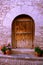 Semicircular entrance to the stone house, wooden antique door, flowers in pots.