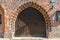 Semicircular gate in an old building made of red masonry with a modern bell and a lamp