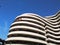 The semicircular white building with curved balconies and terraces on the background of blue sky. modern construction of houses