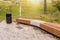 Semicircular wooden bench made of logs on the background of a slope with green grass and trees, autumn Sunny day, Moscow, Russia