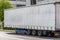 Semitrailer with white tarpaulin without inscriptions, standing on the street.