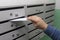 Sending mail, a man puts a letter in the mailbox. Placing letters in the mailbox of an apartment building, close-up. Russia