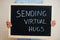 Sending virtual hugs. Coronavirus concept. Boy hold inscription on the board