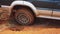 Sendrisoa, Madagascar - April 28, 2019:  4WD car pass slowly over holes in muddy ground, detail on rear wheel. Roads are in awful