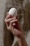 Senile hand holds a white chicken egg