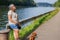 Senior adult female tourist together with her dachshund taking a break next to Albert canal