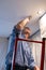 Senior adult man painting ceiling of kitchen