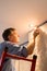 Senior adult man painting ceiling of kitchen