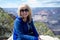 Senior adult woman 60s sits and poses at a viewpoint along the South Rim of the Grand Canyon National Park while on vacation