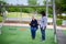 Senior adult woman enjoys swinging in the playground while carer protecting her