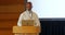 Senior African American businessman speaking on stage at podium in auditorium 4k