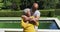 Senior african american couple in love smiling and embracing by swimming pool in sunny garden