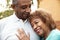 Senior African American  husband and wife embracing outdoors, close up