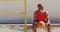 Senior african american man exercising sitting and playing with basketball