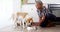 A senior African American woman feeds her dog at home