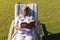 Senior african american woman reading book in deckchair in sunny garden