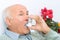 Senior aged man uses inhaler to cure his ache