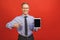 Senior aged middle aged man holding tablet with blank screen isolated over red background