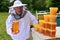 Senior apiarist presenting jar of fresh honey in apiary
