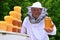 Senior apiarist presenting jar of fresh honey in apiary