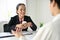 A senior Asian businesswoman or female recruiter interview a male candidate in the office