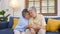 Senior asian couple comforting each other from depressed emotion while sitting on sofa at home living room, old retirement