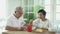 Senior Asian couple having breakfast together in dinner room. 70s retired elderly man and woman reading newspaper
